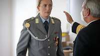 Soldatin steht in der Frint eines weiteres Soldaten.