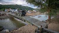 Ein Lkw der Bundeswehr fährt über eine errichtete Behelfsbrücke im Ahrtal.