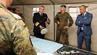 Ein Marineoffizier steht mit anderen Soldaten in einem zelt und spricht.