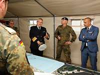 Ein Marineoffizier steht mit anderen Soldaten in einem zelt und spricht.