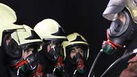 Five people in fire suits talk to each other.