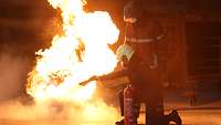 A person in a protective suit trains to extinguish fires.