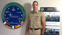 A soldier is standing in a hallway in front of a US agency's emblem