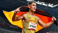 Ein Para-Sportler auf der Tartanbahn mit Deutschlandfahne.