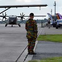 Ein belgischer Soldat, von hinten zu sehen, steht vor zwei Militärflugzeugen auf einem Flugfeld
