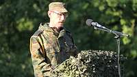 Ein Soldat steht hinter einem Rednerpult und spricht in ein Mikrofon.