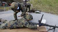 Ein Soldat kontrolliert die Waffe eines weiteren Soldaten auf einer Schießbahn.