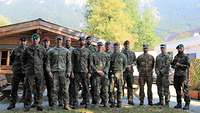 Gruppenbild zahlreicher Soldaten in Flecktarnuniformen haben sich zu einem Gruppenfoto aufgestellt, im Hintergrund ein Berg.