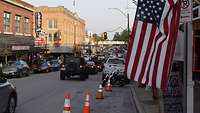 Auf einer Straße in Fort Worth sind viele Autos und eine US-Flagge zu sehen.