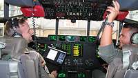 Im Cockpit der C-130J Zwei Soldaten sitzen im Cockpit einer C-130J