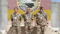 Zwei Soldaten und eine Soldatin vor einem Campschild