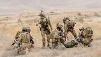Mehrere Soldaten bei einer Einweisung im Gelände in Afghanistan.