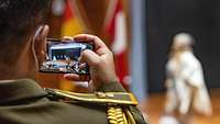International soldier filming stage performance with his smartphone