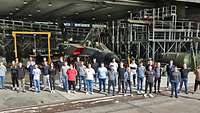 32 junge Menschen stehen bei einem Gruppenfoto vor einer Luftfahrzeughalle. Im Hintergrund steht ein Tornado.