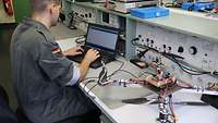 Ein Elektroniker programmiert mit einem Laptop einen Quadrokopter.