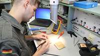 Ein Elektroniker lötet an einer Platine.