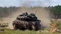 Ein Kampfpanzer überquert in voller Fahrt eine Freifläche auf dem Truppenübungsplatz Gaižiŭnai, Litauen