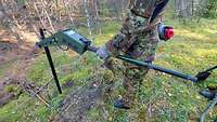 Ein Soldat steht mit einer Tiefensonde im Wald.