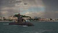 a dark grey submarine vessel in front of a town