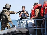 Ein voll besetztes Gummiboot mit uniformierten Soldaten und Zivilisten in Schwimmwesten.