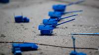 Großaufnahme: Auf grauem Sand stehen vier blaue, kleine Modellpanzerhaubitzen.