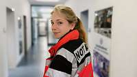Eine Ärztin in Uniform mit Notarztjacke in einem Flur. 