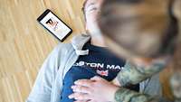 Ein Mann wird von einer Frau reanimiert, daneben liegt ein Smartphone