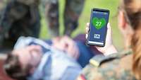 Eine Soldatin hält ein Smartphone in der Hand.