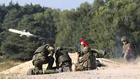 Das Bild zeigt vier Soldaten von hinten, sitzend und kniend, bei einer Übung mit einem Lenkflugkörper.