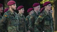 Mehrere Soldaten stehen singend im Stillgestanden in einer Formation. 