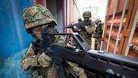 Soldaten mit Gewehren zwischen Containern