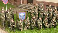 Gruppenbild von Jugendlichen in Uniform, zwischen ihnen das blauweiße Regimentswappen.