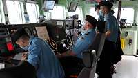 Mehrere Soldaten stehen auf der Brücke eines Schiffes.