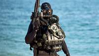 Ein Kampfschwimmer im Neoprenanzug mit Waffe und voller Ausrüstung