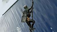Ein Kampfschwimmer klettert an einer Stange an Bord eines Schiffes