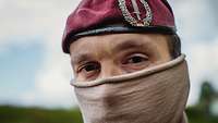 Leutnant, Kommando Spezialkräfte Porträt von einem Soldaten mit Tuch im Gesicht und rotem Barett