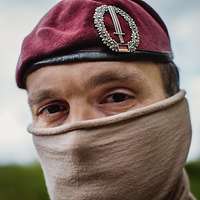 Porträt von einem Soldaten mit Tuch im Gesicht und rotem Barett