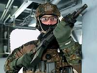 Ein vermummter Soldat mit Waffe in Stellung auf einem Schiff