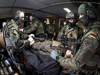 Soldaten unter Deck eines Schiffes stehen um einen liegenden Verwundeten und bereiten diesen für den Transport vor