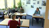 Drei Personen sitzend im Bewerbungsgespräch. Der Soldat notiert etwas und eine Frau hört aufmerksam der dritten Person zu.