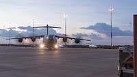 Ein Flugzeug mit leuchtenden Positionslichtern dreht auf einer Betonfläche ein