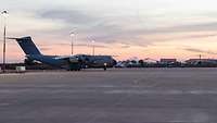 Bei untergehender Sonne fährt ein Flugzeug auf einem asphaltierten Rollfeld