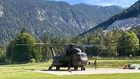 Ein Transporthubschrauber steht auf einer Landefläche zwischen Bergen.
