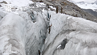 Vier Soldaten klettern eine Eiswand im Berg hoch, drei weitere Soldaten stehen bereits oben.