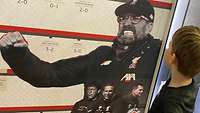 Ein Kind steht vor einer Fußball-Schautafel mit einem Bild von Jürgen Klopp.