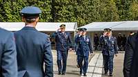 Die drei Generäle Drei Generäle grüßen militärisch und laufen eine Front von Soldatinnen und Soldaten ab.