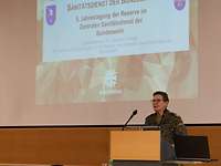 Die Kommandeurin der Sanitätsakademie der Bundeswehr bei ihrem Grußwort Eine Soldatin im Feldanzug steht hinter einem Rednerpult und spricht ins Plenum.