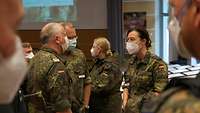 Vier Soldatinnen und Soldaten stehen im Hörsaal und unterhalten sich