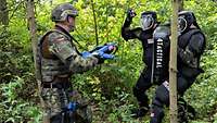 Ein Soldat kämpft mit blauem Übungsgewehr in der Hand gegen zwei schwarz gekleidete Feinddarsteller.