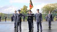 Drei Soldaten stehen in blauer Uniform auf einem Appelllplatz. Sie geben sich gegenseitig die Fäuste.